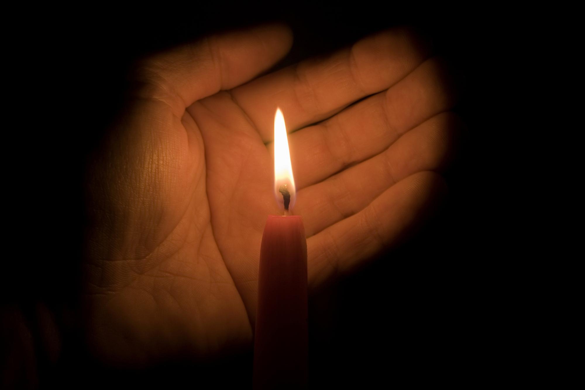 Hand behind a lit candle